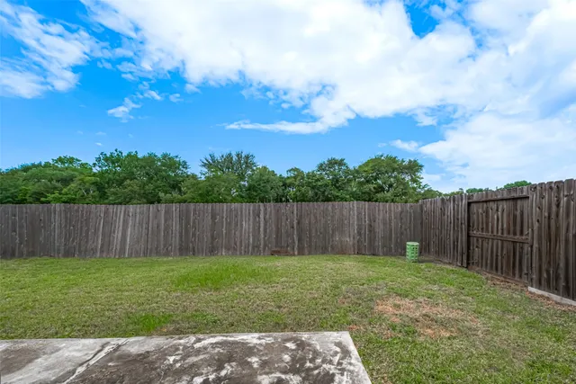 a view of backyard with wooden fence