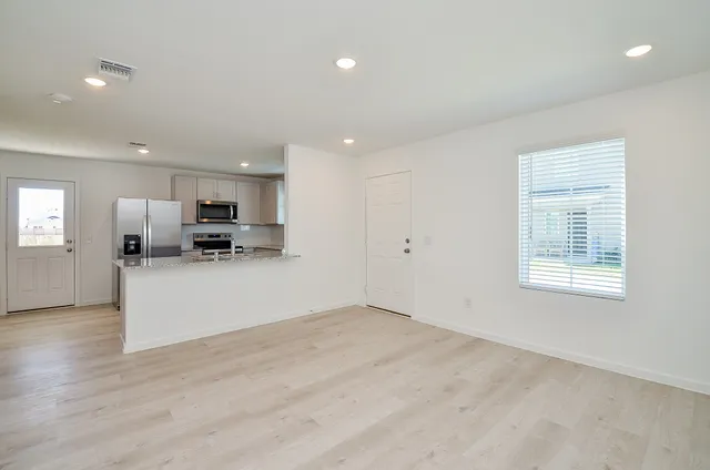 a view of kitchen with stainless steel appliances refrigerator oven and white cabinets