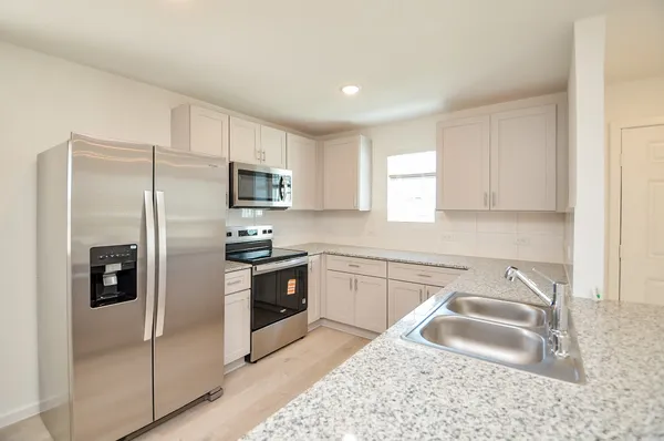 a kitchen with granite countertop a sink stove and refrigerator