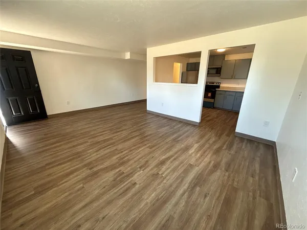 a view of a hallway with wooden floor and kitchen