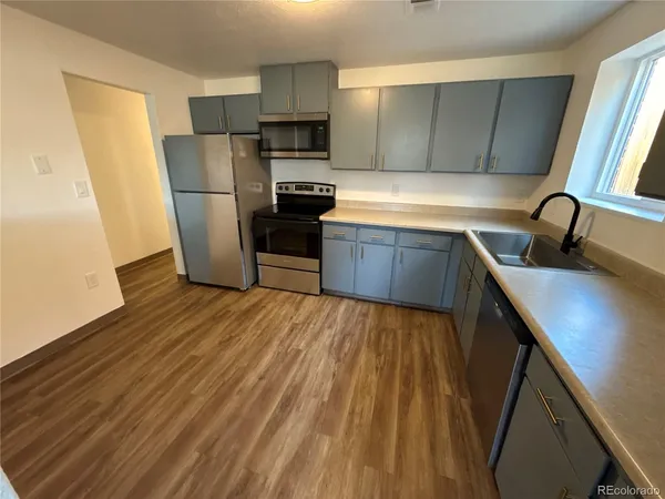 a kitchen with a sink a refrigerator a window and wooden cabinets