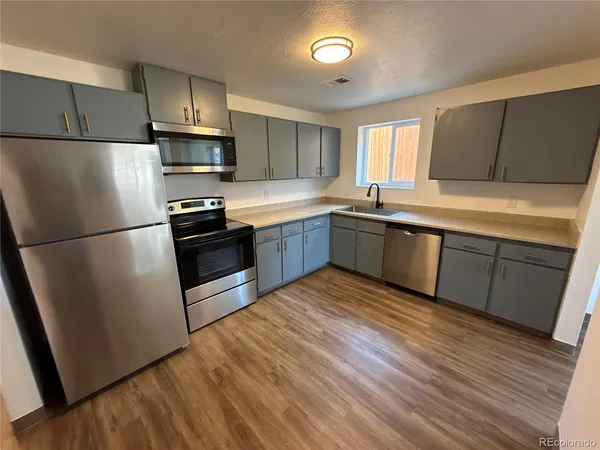 a kitchen with wooden floors stainless steel appliances and a window