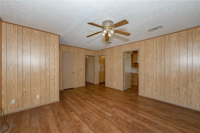 a view of empty room with wooden floor and fan