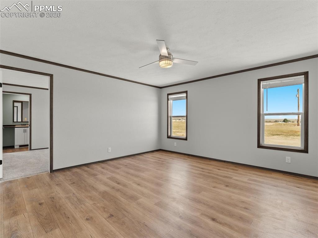 2820 East Ellicott Road South Calhan, CO 80808 - Photo 26 of 39 an empty room with wooden floor ceiling fan and windows