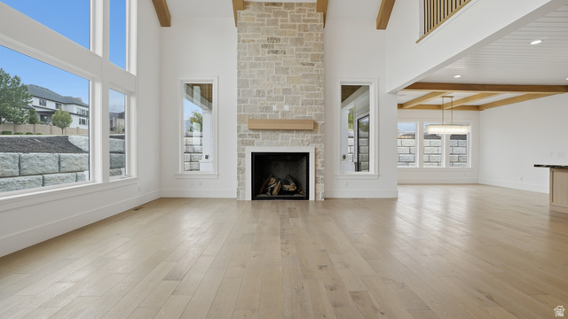 1682 North 1950 W Street, Unit 9 Provo, UT 84604 - Photo 15 of 84 Two-story living area featuring a stacked stone fireplace with a wood mantel, light wood-finish flooring, and expansive windows