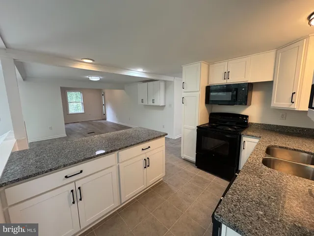 a kitchen with granite countertop a sink and a stove top oven
