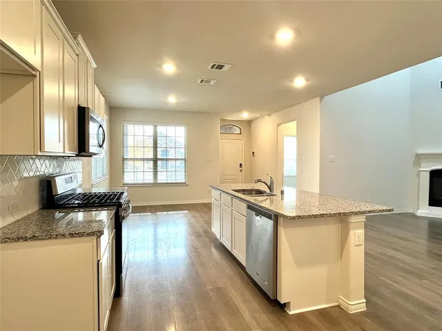 a large kitchen with stainless steel appliances granite countertop a stove a sink and a wooden floors