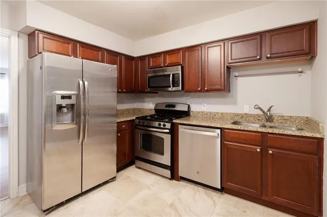 a kitchen with stainless steel appliances granite countertop a refrigerator and a stove top oven