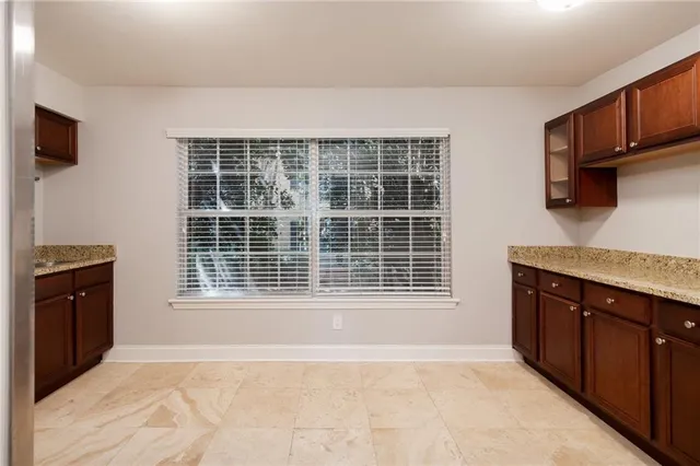 a view of an empty room with a window and a kitchen