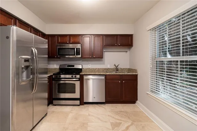 a kitchen with stainless steel appliances granite countertop a refrigerator and a stove top oven