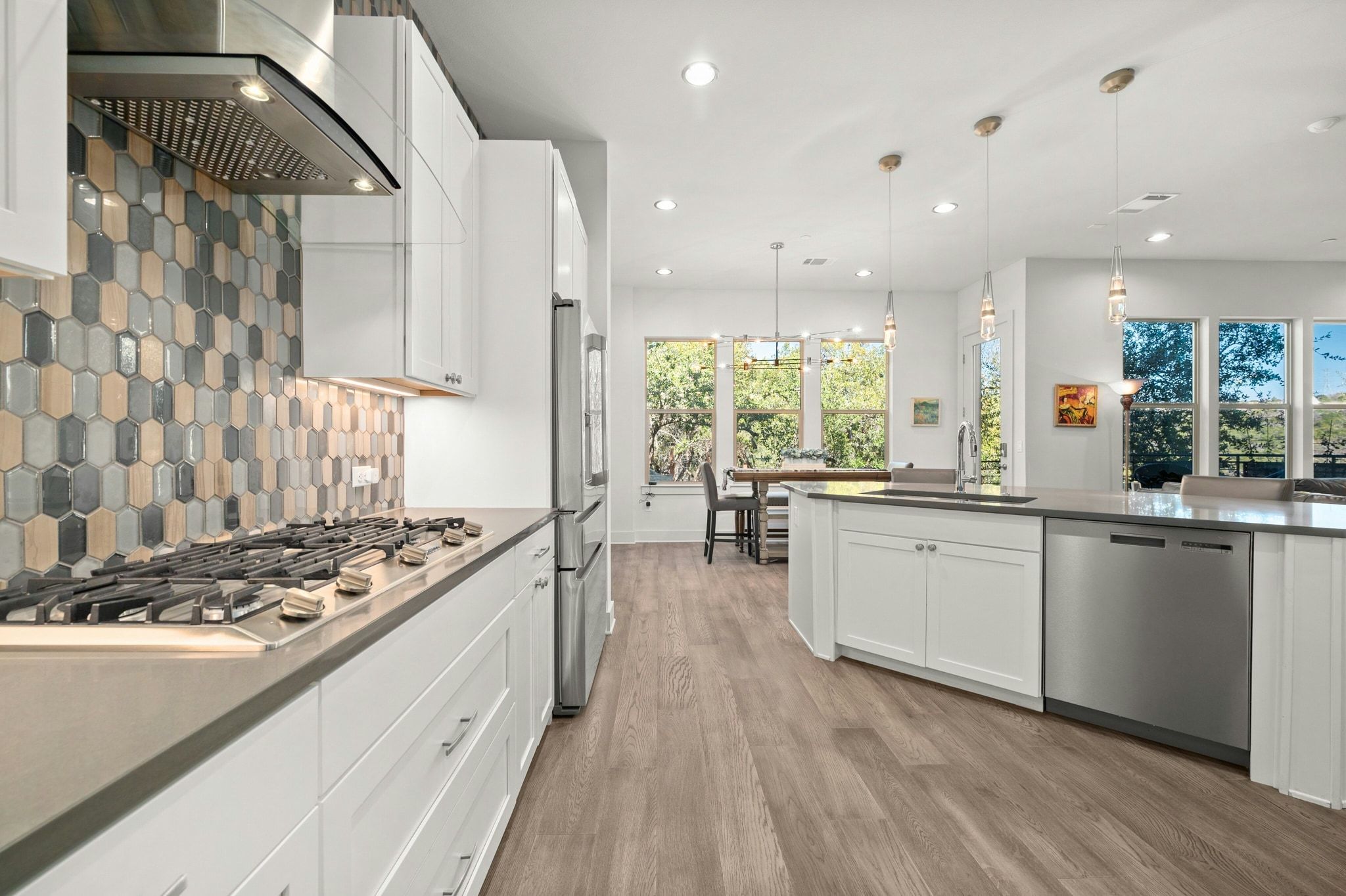 8110 Ranch Road 2222, Unit 92 Austin, TX 78730 - Photo 10 of 40 Contemporary kitchen featuring a gas range with stainless steel hood, decorative tile backsplash, white cabinetry, and wood-finish flooring