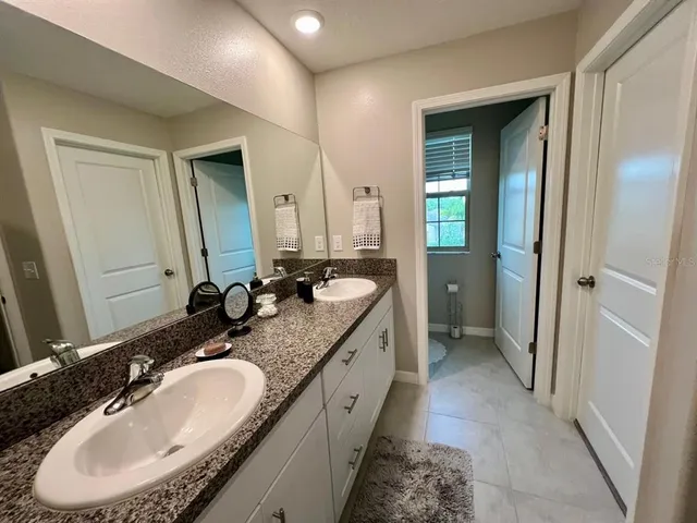 a en suite bathroom with a granite countertop sink and a mirror