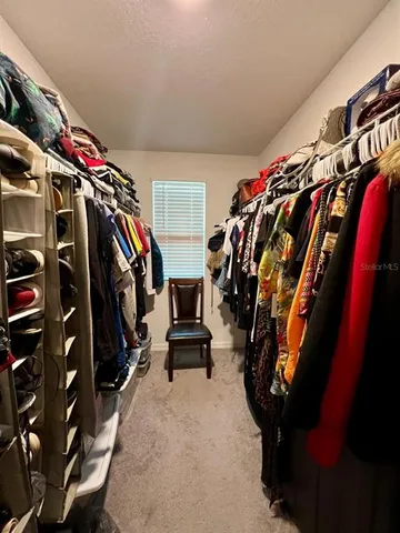 a view of walk in closet with clothes and shoes