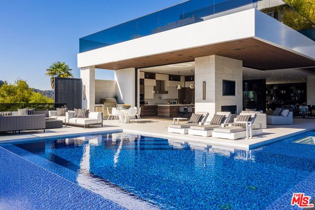 a living room with couches chairs and kitchen view with wooden floor