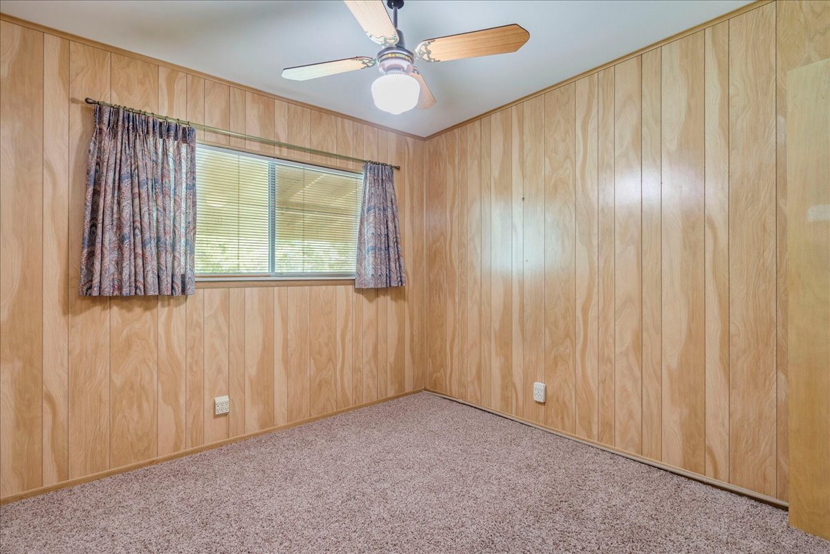 6626 Isabelle Drive Austin, TX 78752 - Photo 19 of 27 Bedroom featuring wood-paneled walls, a window with horizontal blinds, and a ceiling fan with integrated lighting