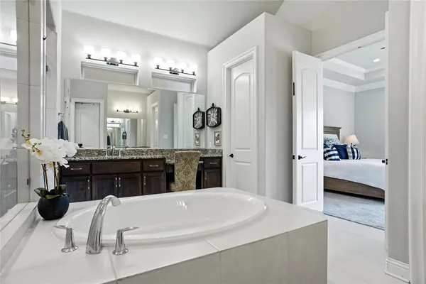 a en suite bathroom with a double vanity sink tub and view bedroom