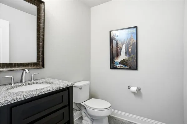 a bathroom with a granite countertop toilet sink and mirror