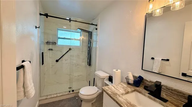 a bathroom with a granite countertop sink toilet and shower