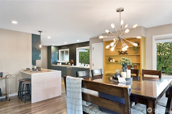 a dining room with wooden floor a chandelier a wooden table and chairs