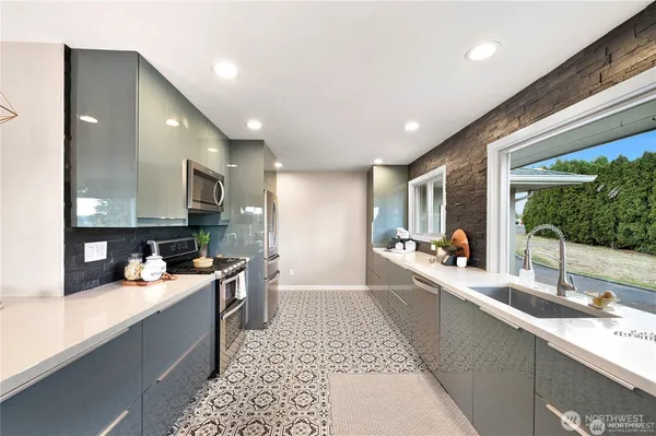 a large white kitchen with stainless steel appliances granite countertop a sink and cabinets