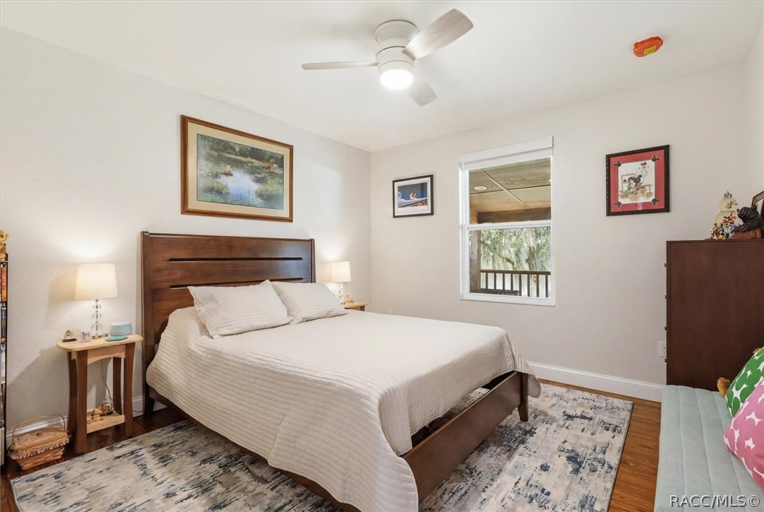 4099 West Ridge Court Dunnellon, FL 34433 - Photo 33 of 49 Comfortable guest bedroom with fan & light & window with view of back yard paradise. Still featuring those 6" baseboard and awesome Pine floors.