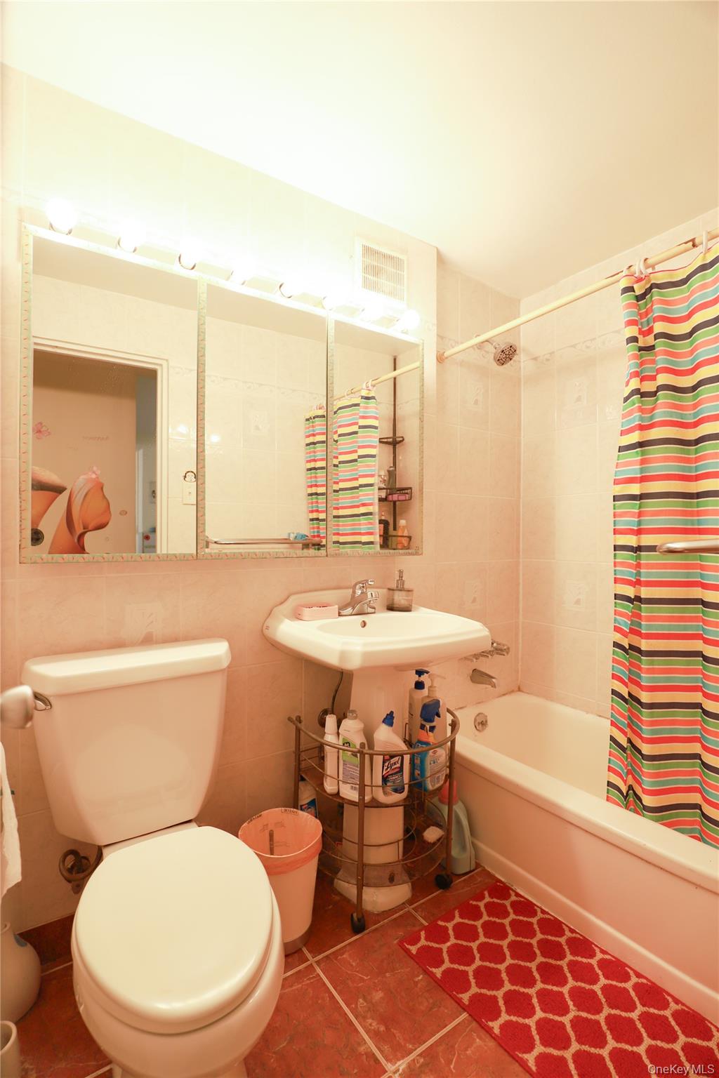 98-25 64th Road, Unit 6F Queens, NY 11374 - Photo 11 of 12 Bathroom featuring a white pedestal sink, ceramic tile flooring, and a full-size bathtub with tiled surround
