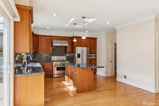 a large kitchen with granite countertop a large counter top stainless steel appliances and cabinets
