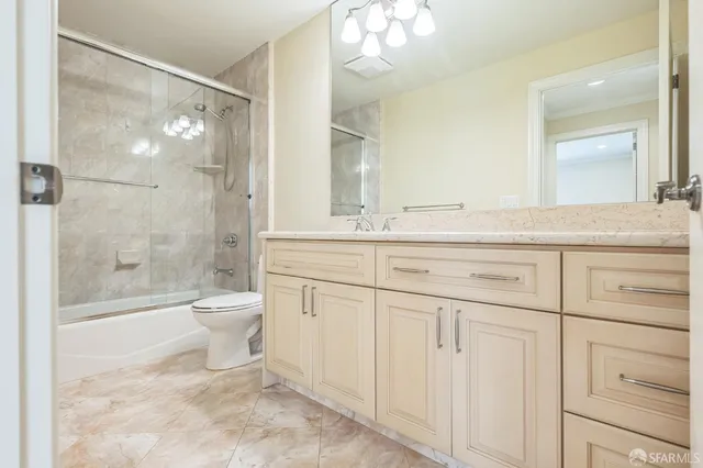 a bathroom with a granite countertop toilet sink and mirror