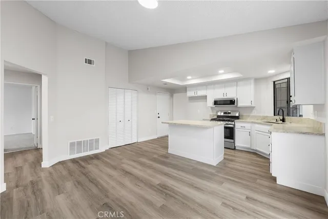 a kitchen with granite countertop a sink cabinets and wooden floor