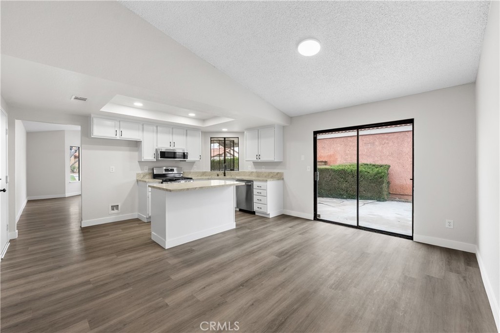 3563 East Ave R-11 Palmdale, CA 93550 - Photo 18 of 36 a view of kitchen with stainless steel appliances granite countertop a stove top oven a sink with white cabinets and wooden floor