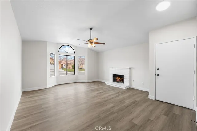 an empty room with windows fireplace and a kitchen view