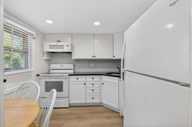 a kitchen with white cabinets and white appliances
