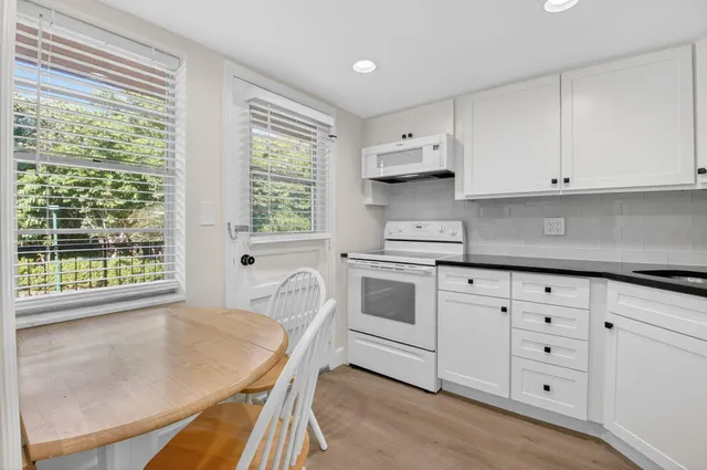 a kitchen with granite countertop white cabinets and white appliances
