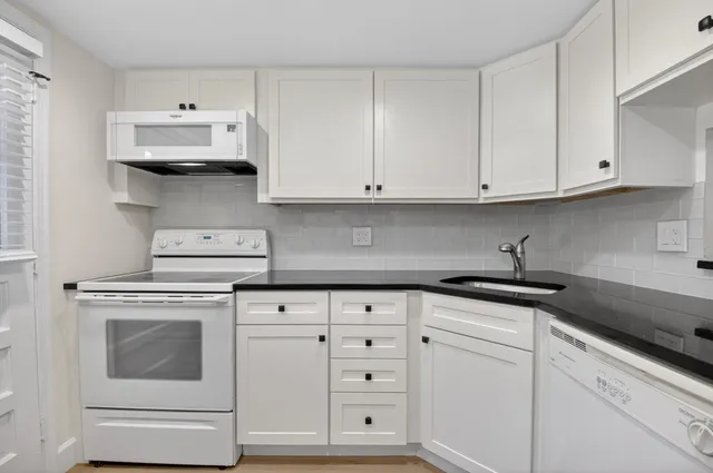 a kitchen with granite countertop white cabinets and white appliances