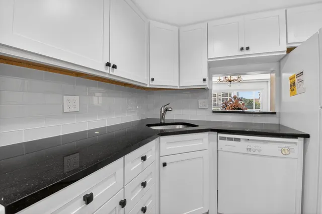 a kitchen with sink a refrigerator and white cabinets