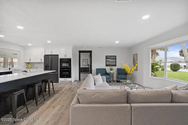 a living room with furniture kitchen view and a large window
