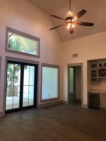 an empty room with wooden floor fan and windows