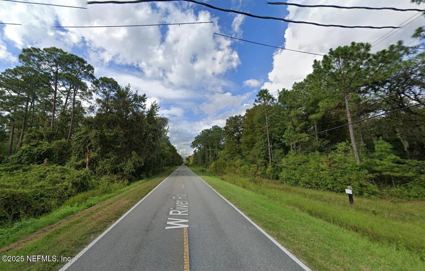a view of a street with a yard and a street view