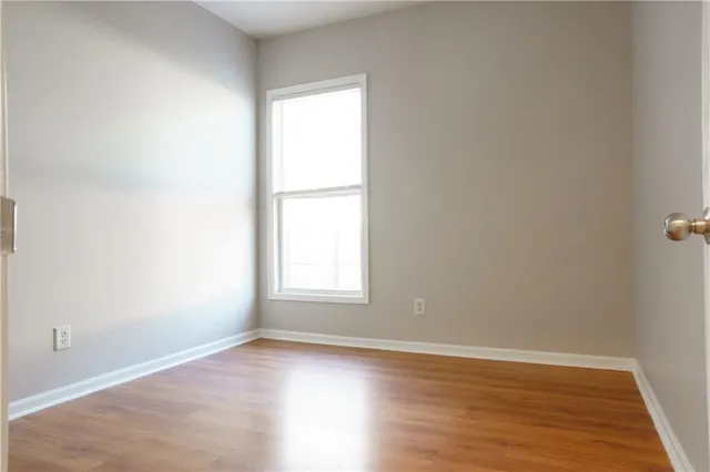 an empty room with wooden floor mirror and closet