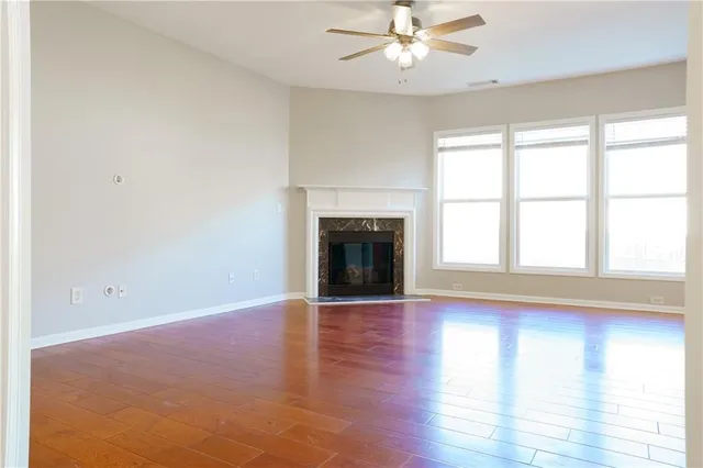 an empty room with wooden floor fan and windows