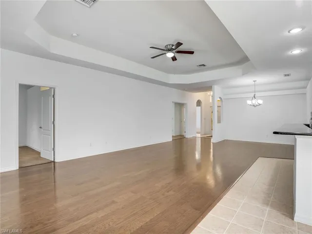 a view of an empty room with wooden floor and a ceiling fan