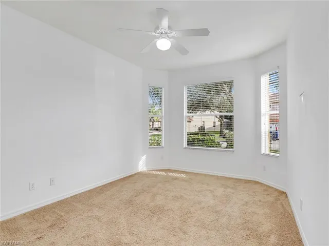 an empty room with windows and ceiling fan view