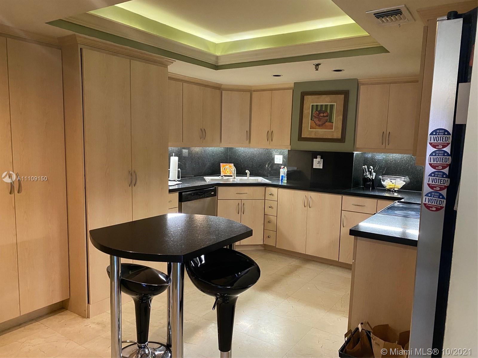 650 Ocean Drive, Unit 9E Key Biscayne, FL 33149 - Photo 3 of 5 a kitchen with a table chairs and a refrigerator