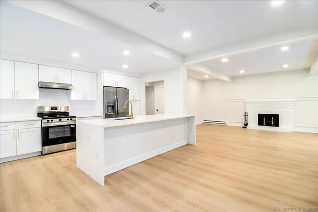 a large white kitchen with kitchen island a sink a stove and a refrigerator