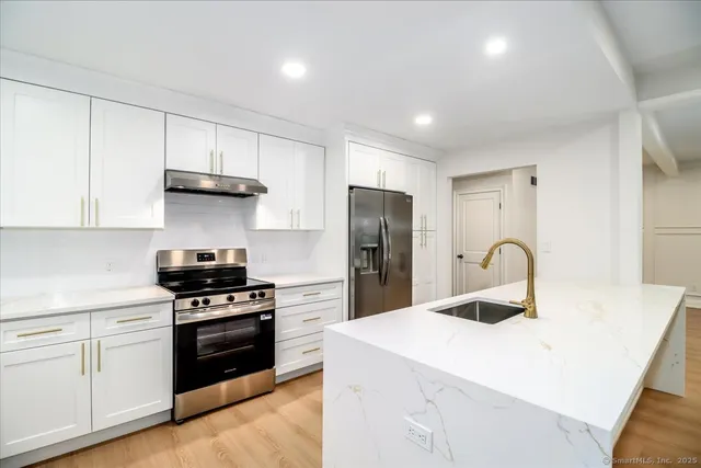 a kitchen with kitchen island stainless steel appliances a sink a stove and refrigerator