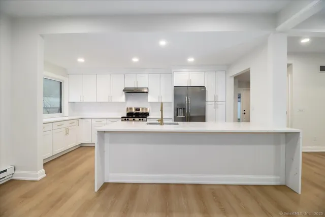a large white kitchen with wooden floors and white cabinets