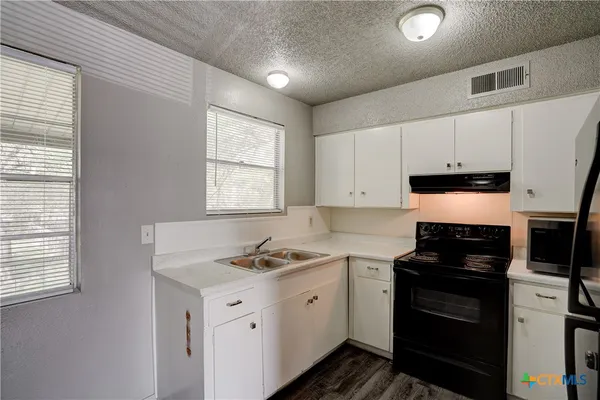 a kitchen with granite countertop white cabinets and black appliances