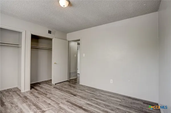a view of an empty room with wooden floor and closet
