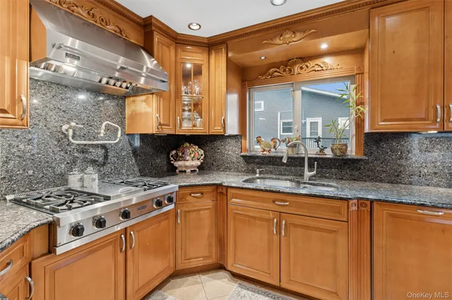 a kitchen with granite countertop a sink a stove and cabinets