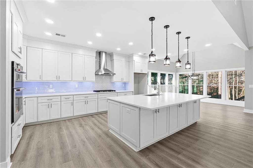 2152 Paces Vale Place Lawrenceville, GA 30043 - Photo 2 of 39 a kitchen with stainless steel appliances granite countertop a stove a sink and white cabinets with wooden floors
